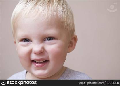 Blonde toddler scrunches his face in laughter