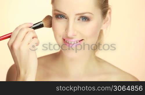 blonde woman applying blusher