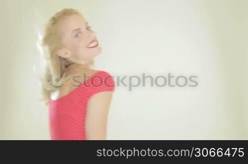 Blonde woman holding a fashionable red high heeled platform shoe walking past the camera