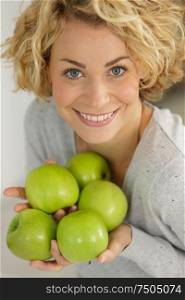 blonde woman holding green apples