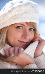Blonde woman in a cream jumper and hat