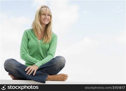 Blonde woman in a green sweater sitting outdoors