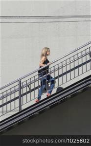 Blonde woman in casual wear walking up stairs outdoor in the city