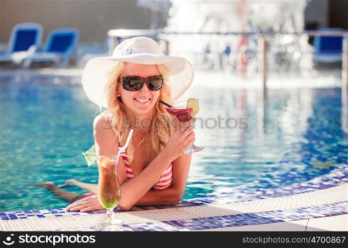 Blonde woman in hat at the swimming pool. Woman in swimming pool