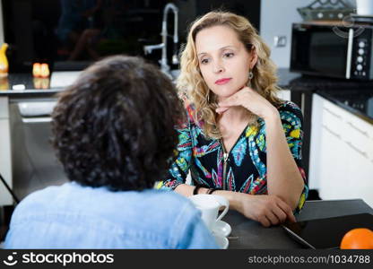 blonde woman in kitchen talking with her friend