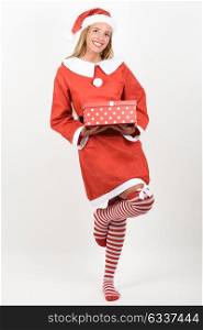 Blonde woman in Santa Claus clothes smiling with gift box in her hands. Young female with blue eyes wearing striped socks, isolated on white