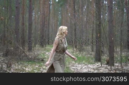 blonde woman in the forest looking from behind the tree
