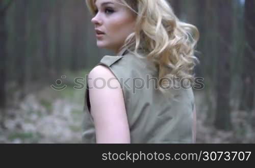 blonde woman in the forest running looking behind scared