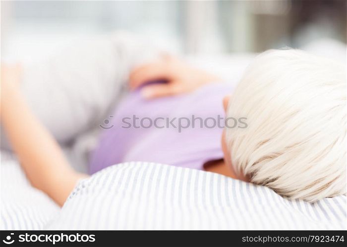Blonde woman is lying in the bed at home
