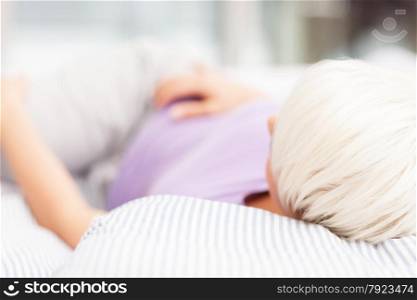 Blonde woman is lying in the bed at home