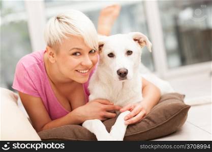 Blonde woman is playing with her dog at home