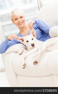 Blonde woman is playing with her dog at home