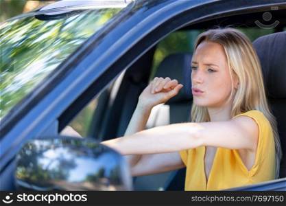 blonde woman makes anxious facial expression while driving