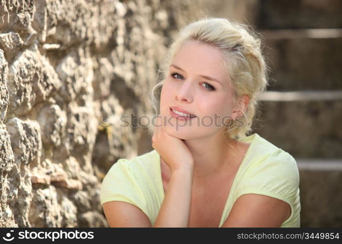 Blonde woman next to stone wall
