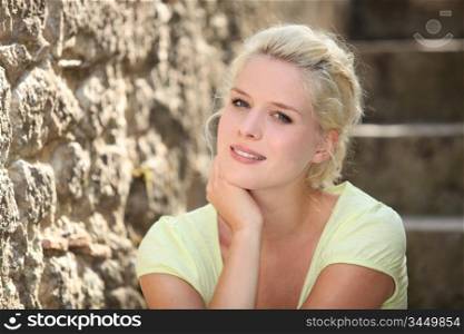 Blonde woman next to stone wall