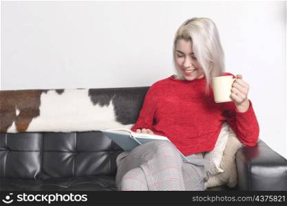 Blonde woman reading a book on leather couch