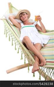 blonde woman resting and drinking in a hammock