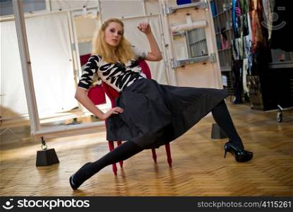 Blonde woman sits posing on chair