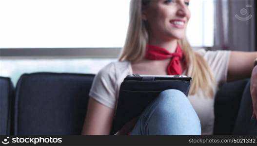 Blonde Woman Sitting On A Sofa Using Her Tablet