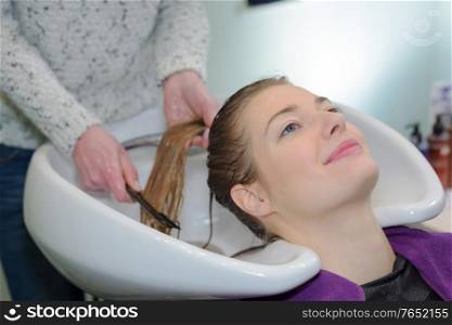 blonde woman washing hair in a salon