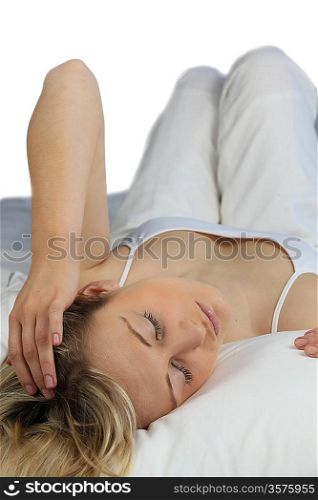 Blonde woman wearing white and lying on a white bed