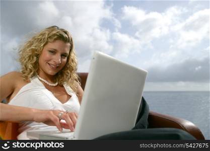 Blonde woman with a computer in front of the sea