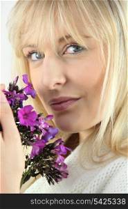 Blonde woman with a sprig of purple wild flowers