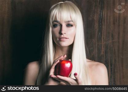 Blonde woman with apple. Young pretty blonde woman with long hair holding red apple on wooden background