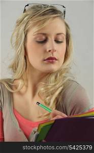blonde woman with downcast eyes writing