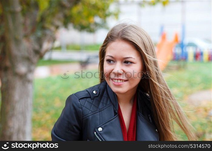 Blonde woman with leather jacket in a park