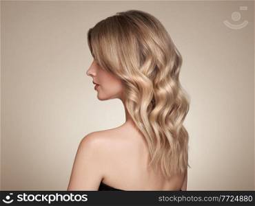Blonde woman with long and shiny curly hair. Beautiful model girl with curly hairstyle. Care and beauty hair products