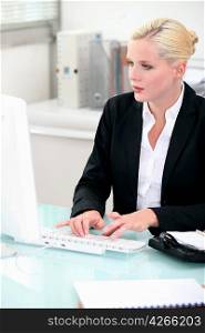 Blonde woman working at a desktop computer