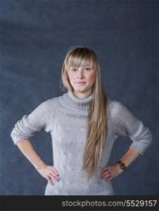Blonde women looking at camera studio shot. Portrait of elegant young woman in a jumper on a dark background