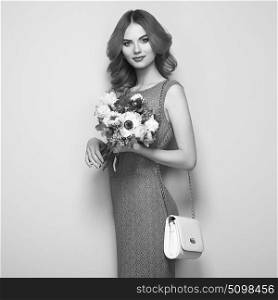 Blonde young woman in elegant red dress. Girl posing with handbag. Jewelry and hairstyle. Lady with spring bouquet of flowers. Fashion Black and White photo