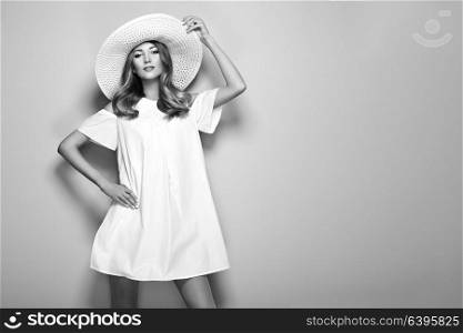 Blonde Young Woman in elegant white Dress and Summer Hat. Girl posing on a White Background. Jewelry and Clothing. Fashion photo