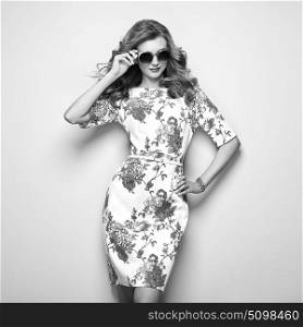 Blonde young woman in floral spring summer dress. Summer floral outfit. Stylish wavy hairstyle. Fashion photo. Glamour lady in stylish sunglasses. Black and White photo
