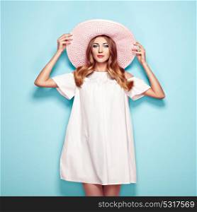 Blonde Young Woman in Summer White Dress and Summer Hat. Girl Posing on a Turquoise Background. Hairstyle and Clothing. Fashion Photo