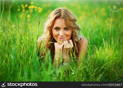 blonde young woman lays on green grass. blonde on grass