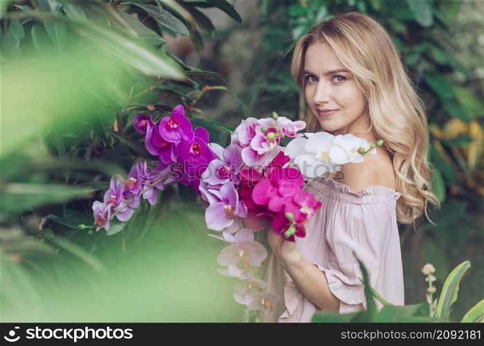 blonde young woman standing garden holding orchid