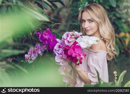 blonde young woman standing garden holding orchid