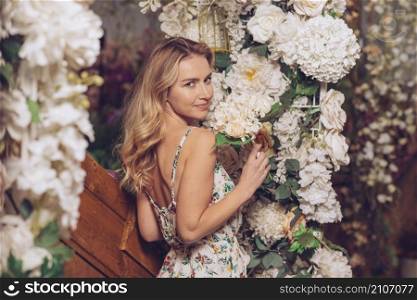 blonde young woman standing near white flower decoration
