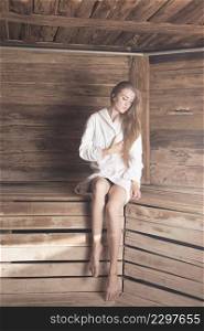 blonde young woman with eye closed sitting wooden bench sauna