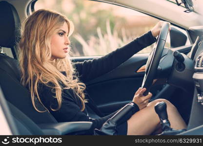 Blondie young girl driving a sport car looking at the road