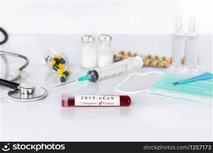 Blood test tube with the Coronavirus disease for virus test and research. Blood test tube with protective masks, medicines, thermometer, stethoscope and syringe on a white background.