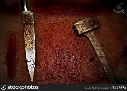 Bloodied metal hammer and knife lying in blood closeup