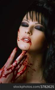 bloody vampire girl with delight on face on a black background