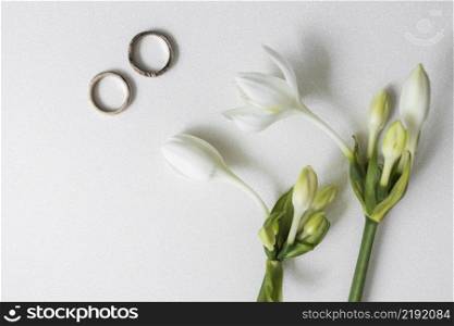 blooming flowers with two wedding rings white background