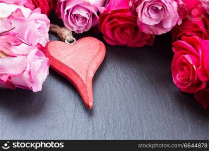 blooming fresh  pink roses with red heart on black background with copy space. roses with red heart