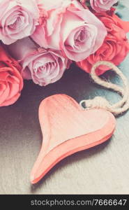 blooming pink roses laying on black stone table with red heart, in earth tones. red and pink roses on table