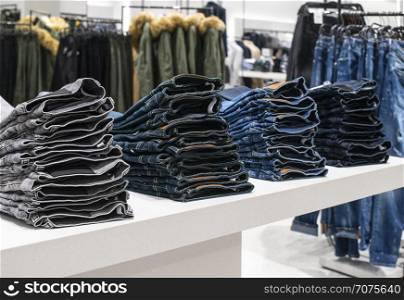 Blouses and jeans on shelf in fashion clothing store. Casual clothes in shop. Commercial and fashion concept.
